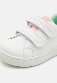 Weiße Leder Sneakers mit rosa und mintfarbenen Akzenten. Verfügt über zwei Klettverschlüsse und eine strukturierte Sohle. Branding sichtbar auf dem Riemen und der Seite.
