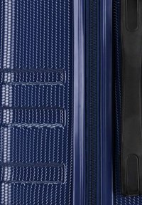Valigia blu navy con ruote, dotata di un motivo esagonale texture, zip liscia e maniglia in plastica dura nera. Presenta scanalature verticali su un lato.