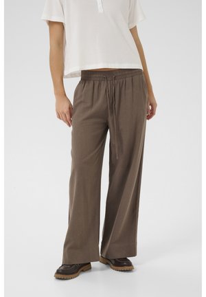 Braune weite Hosen mit elastischem Bund und Kordelzug. Kombiniert mit einem weißen kurzärmeligen Oberteil. Glatte Stofftextur, lockere Passform.