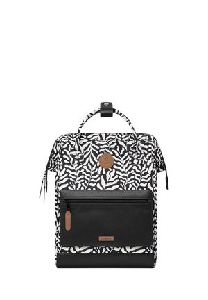 Zebra-patterned backpack in black and white with a textured black bottom, front zip pocket, and a round logo patch. Features dual handles and zippers.