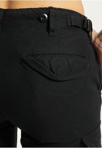 Black pants with a textured fabric, featuring a button closure, belt loops, and a patch pocket on the back with a curved flap.