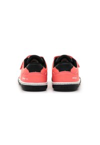 Sneaker rosse e nere con un materiale superiore liscio, fascia in velcro, suola intermedia bianca e branding minimale sul tallone.