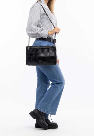 Black patent handbag with horizontal ribbed texture and chain strap, worn crossbody. Paired with high-waisted light blue jeans and black boots.