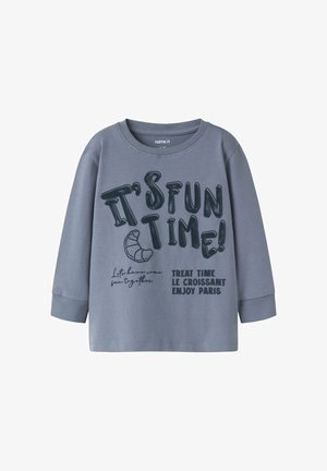 Szary t-shirt z długim rękawem wykonany z bawełny, z okrągłym dekoltem. Posiada dużą czarną grafikę: „CZAS NA ZABAWĘ!” oraz „CZAS NA PRZYSMAK LE CROISSANT CIESZ SIĘ PARYŻEM.”