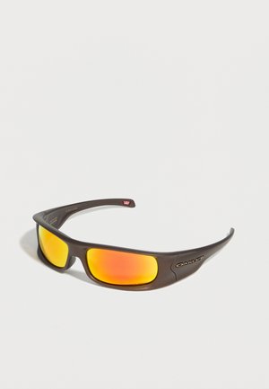 Gafas de sol Oakley negras envolventes con lentes reflectantes naranjas sobre un fondo claro y liso.