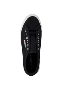 Black canvas sneaker with white rubber sole, round toe, six metallic eyelets, black laces, and branding tag on the side.