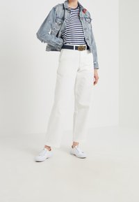 Jeansjacka i ljusblått med broderi, marinblå randig t-shirt, vita högmidjade byxor och vita sneakers. Avslappnad outfit.