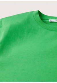 Groene katoenen trui met een geribde ronde hals en een gladde textuur. Close-up benadrukt kleur en stofdetails.