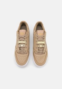 Beiga lädersneakers med guldiga detaljer, perforerad tå, snörningssystem och kontrasterande vit sula. Diskret varumärkeslogotyp på tungan.