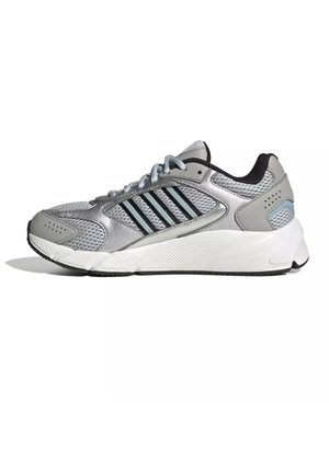 Zapatilla deportiva gris y plateada con detalles negros, parte superior de malla y material sintético, suela blanca acolchada y cierre con cordones, mostrada de lado.