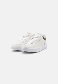 Baskets en cuir blanc avec une texture lisse, bout rond, design à lacets et accent vert au niveau du talon. Présente le logo sur la languette.