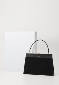 Sac à main en suède noir avec une forme structurée, doté d'une poignée supérieure et de quincaillerie dorée. Accompagné d'une boîte blanche avec un logo.