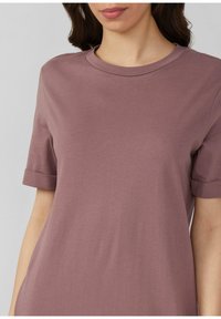 Majica kratkih rukava s okruglim izrezom u umirujućoj mauve boji, izrađena od mekanog pamuka. Ima preklopljene rukave i opušteni kroj.