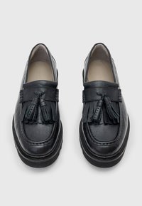 Schwarze Leder-Loafer mit rundem Zehenbereich, flacher Sohle und dekorativen Quasten an der Vorderseite. Glatte Textur und detaillierte Nähte.