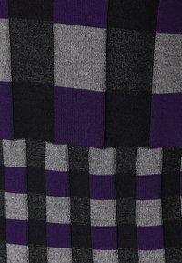 Tissu tricoté présentant un motif à carreaux en nuances de violet, noir et gris. La texture est légèrement en relief avec un mélange de sections lisses et côtelées.