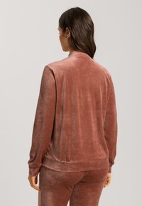 Růžová, měkká sametová bunda s volným střihem, dlouhými rukávy a žebrovým lemem. Navržena s jemným leskem a hladkou texturou.