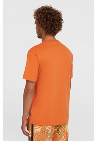 Orange kortærmet t-shirt lavet af bomuld, med et klassisk crew neck design og en glat tekstur. Ingen synlige logoer eller mønstre.