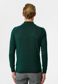 Dunkelgrüner, taillierter Pullover mit langen Ärmeln, geripptem Kragen und Bündchen. Glatte Strickstruktur und Raglanärmel-Design.