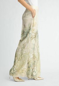 Lichte, luchtige broek in een bleekbeige kleur met groene tropische loofpatronen. Voorzien van zijzakken en een ontspannen pasvorm. Gecombineerd met glanzende gouden schoenen.