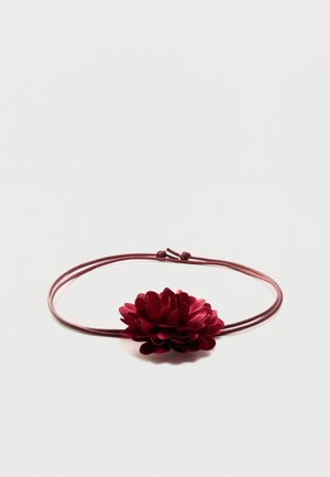 Bracelet en corde fine marron foncé réglable avec une fleur en tissu marron foncé détaillée en son centre sur un fond blanc uni.