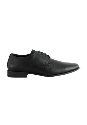 Zapato de vestir de cuero negro con punta afilada, acabado suave, costuras sutiles y un tacón bajo en forma de bloque. Presenta seis ojetes para los cordones.