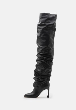 Zwarte leren over-de-knie laars met een slouchy ontwerp, puntige neus en een stilettohak. Beschikt over een zachte textuur en geraffineerde details.