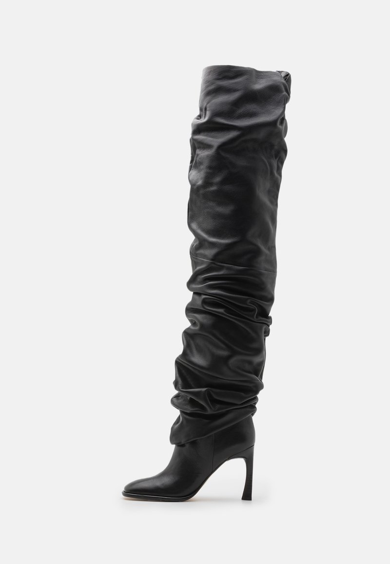 Black leather over-the-knee boot with a slouchy design, pointed toe, and a stiletto heel. Features soft texture and gathered detailing.