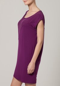 Lila klänning med kort ärm och lös passform, rund halsringning och slät yta; når strax ovanför knäet. Enkel, odekorerad design.