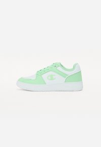 Scarpa sportiva bianca e verde menta. Presenta un materiale sintetico liscio, punta rotonda, suola piatta in gomma e dettaglio del logo sul lato.
