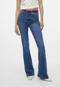 Blå utsvängda jeans i denim, med fem fickor, ett rött bälte och en hög midja. Slät textur och minimal slitage.