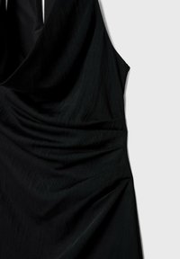 Robe noire sans manches avec encolure drapée et détails de tissu froncés sur un fond clair uni.