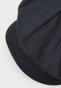 Dark blue cap with a textured linen upper and a solid fabric brim, featuring pleated design details for added visual interest.
