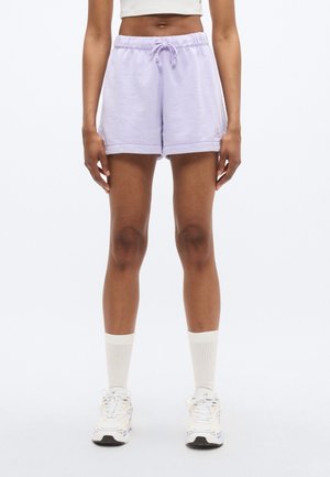 Lniane krótkie spodenki z elastycznym pasem i sznurkiem. Charakteryzują się podwiniętymi brzegami i małym logo z boku. Noszone z białymi skarpetkami i trampkami.