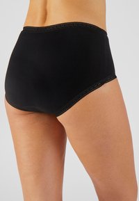 Bragas de algodón negras con un diseño de talle alto, que presentan un borde decorativo de encaje con forma de concha a lo largo de las aberturas de las piernas y de la cinturilla.