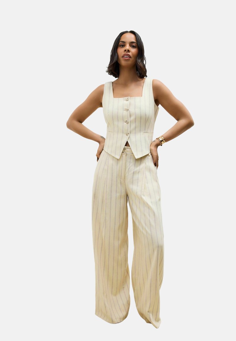 Cremefarbenes, gestreiftes Anzug-Outfit mit einer taillierten Weste mit quadratischem Ausschnitt und fünf Knöpfen, kombiniert mit einer weiten Hose.