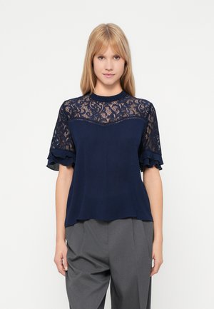 Marinebluse mit einer Spitzenoberfläche, die mit floralen Mustern verziert ist, kurzen, rüschigen Ärmeln und einem lockeren Schnitt sowie einer glatten Textur.