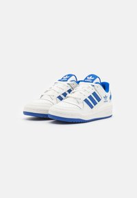 Adidași albi cu accente albastre, având trei dungi albastre, interior căptușit și talpă din cauciuc texturată pentru aderență. Design clasic sport.