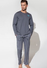 Szara bluzka z długim rękawem z turkusowym logo psa, połączona z granatowymi spodniami w białą kratę. Casualowy, lekkim materiał, luźny krój.