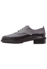 Šedá plátěná bota s černými koženými akcenty, designem wingtips, kulatými šňůrkami a blokovým podpatkem. Lehký strukturovaný svršek a gumová podrážka.