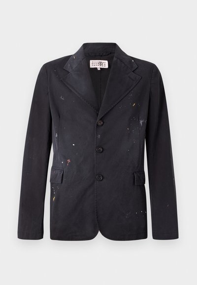 Črn bombažni blejzer s krojem po meri, ki ima razrezan ovratnik, štiri gumbe in barvne madeže čez tkanino.