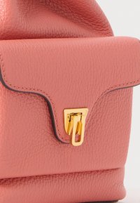 Bolsa de mão de pele texturada rosa com fecho de aba, hardware dourado e costura contrastante em preto. Design compacto com uma silhueta elegante.