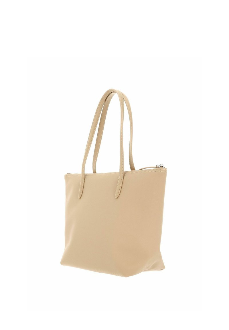 Beige leather tote bag with two long handles and a top zipper closure, shown against a white background.