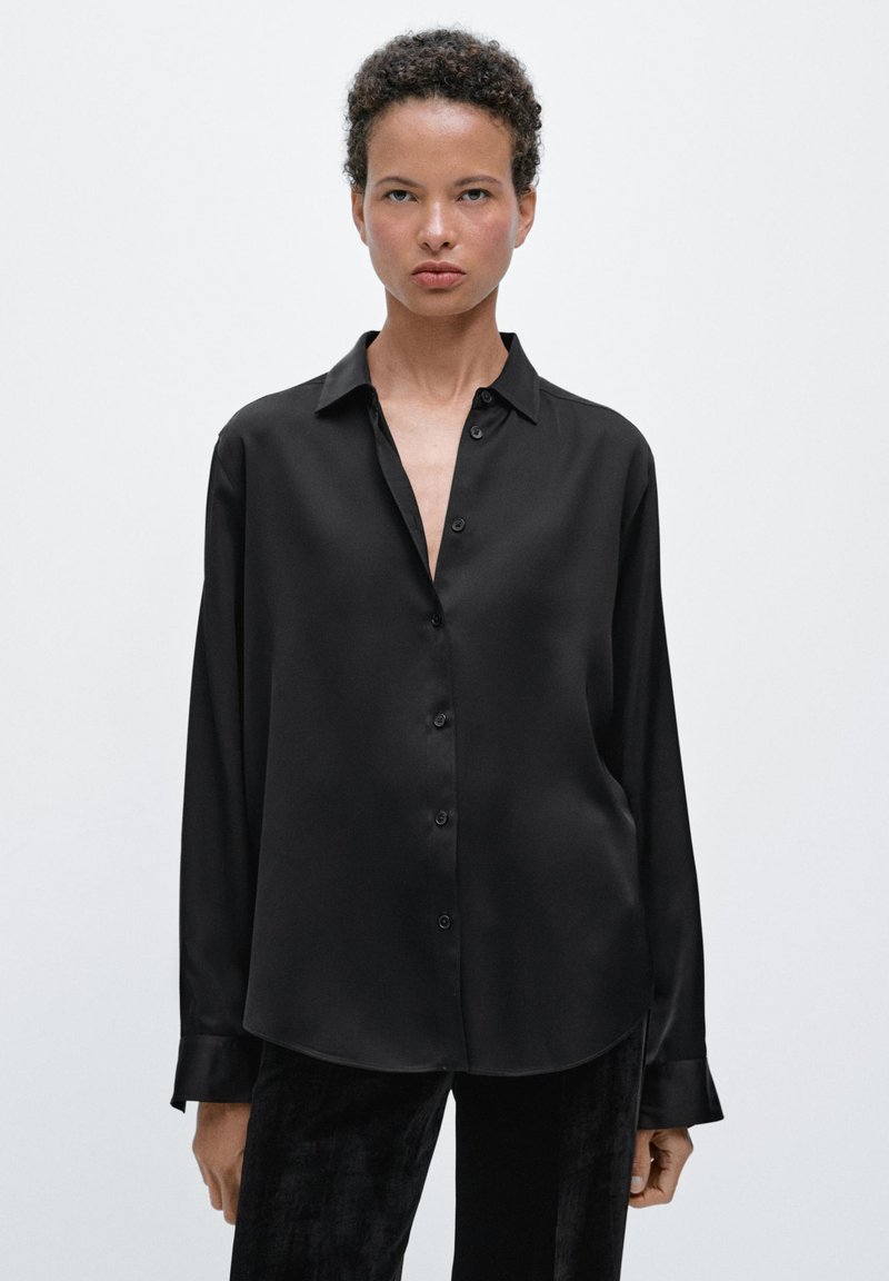 Button-up black satin shirt with a collar, featuring a loose design, long sleeves, and a smooth texture.