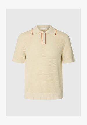 Kermanvärinen neulottu lyhythihainen poolopaita, jossa teksturoidtu kangas, kaksinappinen nappilista ja ohuet ruosteenväriset raidat kauluksen reunoissa ja nappilistassa.