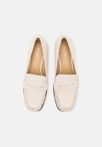 Beige leren loafers met gestikte details en zwarte rubberen zolen. Heeft een ronde neus en een minimalistisch ontwerp. Michael Kors branding aan binnenkant.