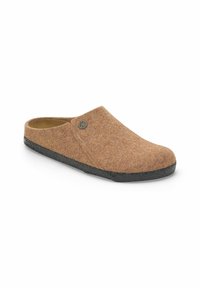 Zoccolo in felt marrone con texture liscia, punta arrotondata e suola in gomma nera. Presenta un piccolo emblema sul lato per un tocco di dettaglio in più.