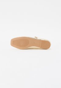 Shoe plano com um upper de cor clara e sola de borracha bege. Apresenta um solado texturizado para aderência e um design simples.