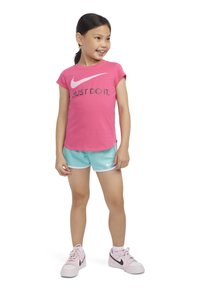 Ροζ μπλούζα Nike με λευκό λογότυπο και κείμενο "JUST DO IT," συνδυασμένη με μέντα πράσινα σορτς και ροζ αθλητικά παπούτσια με σκούρο λογότυπο.