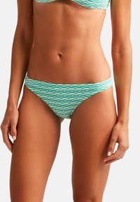 Bikini de fondo con una base de color verde azulado claro que presenta un patrón de diamantes en blanco. Hecho de material elástico, diseñado con una silueta de tiro medio.