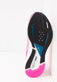 Scarpa da corsa con suola in gomma nera testurizzata, parte superiore prevalentemente rosa, dettagli bianchi e un elemento blu contrassegnato "PROPLATE."
